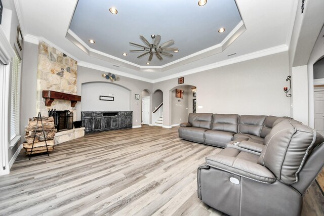 living room with ornamental molding, light hardwood / wood-style floors, a fireplace, and a tray ceiling