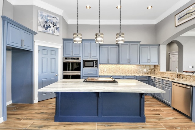 kitchen with decorative light fixtures, stainless steel appliances, and a center island