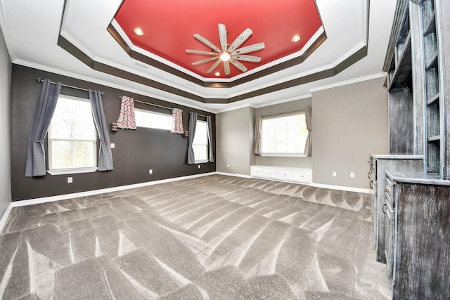 unfurnished living room featuring ceiling fan, carpet flooring, crown molding, and a raised ceiling