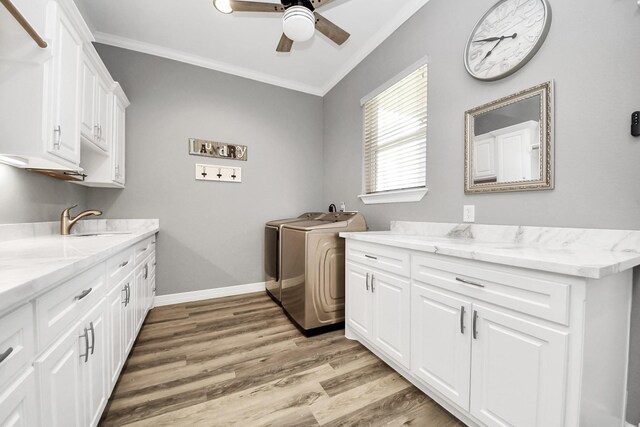 laundry room with crown molding, cabinets, washing machine and dryer, and light wood-type flooring