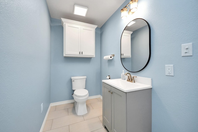 bathroom with toilet, vanity, and tile patterned flooring