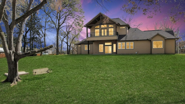 back house at dusk with a balcony and a lawn