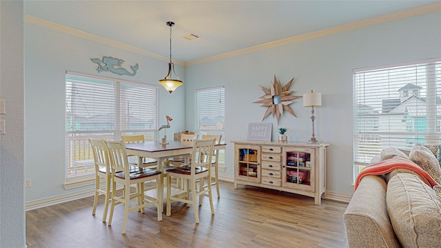 dining room featuring crown molding, a healthy amount of sunlight, and hardwood / wood-style floors