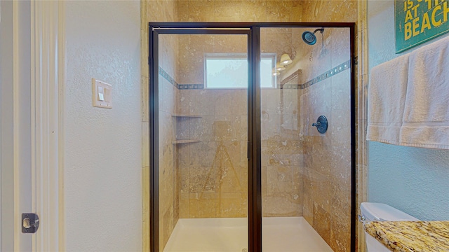 full bathroom with a stall shower, a textured wall, and toilet