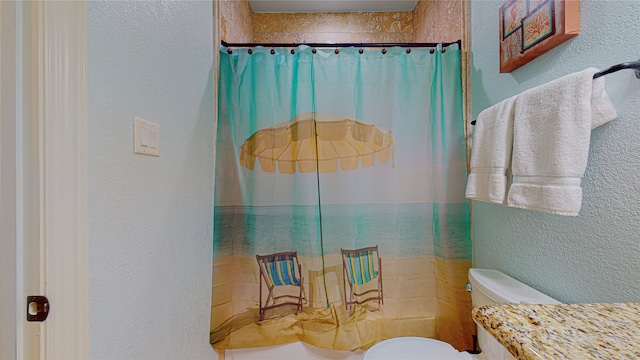 bathroom featuring a shower with curtain, a textured wall, vanity, and toilet