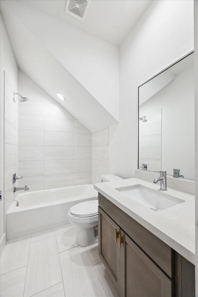 full bathroom with tiled shower / bath combo, vanity, lofted ceiling, and toilet