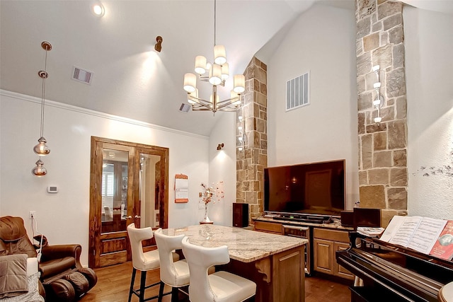 kitchen featuring a kitchen island, wood-type flooring, lofted ceiling, a kitchen breakfast bar, and light stone countertops