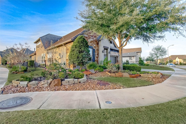 view of front facade featuring a garage, driveway, fence, and a residential view