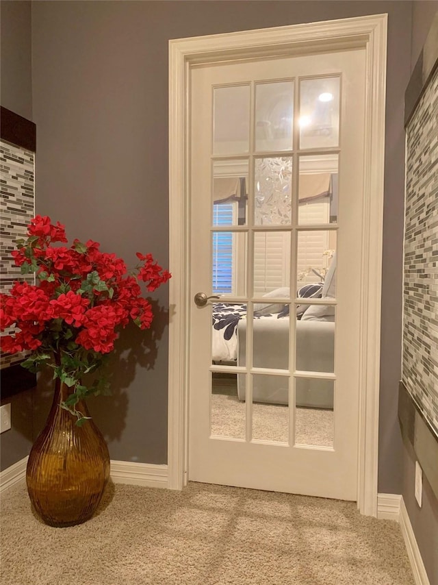 doorway to outside with baseboards and carpet flooring