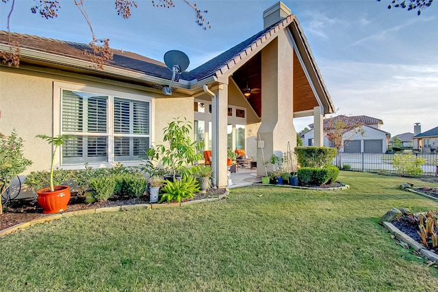 rear view of property with ceiling fan, a yard, and a patio