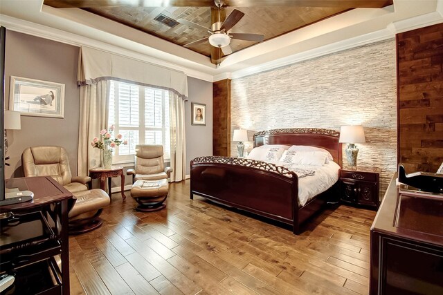 bedroom with ceiling fan, ornamental molding, a tray ceiling, and light hardwood / wood-style flooring