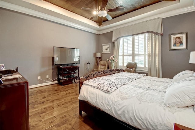 bedroom with a raised ceiling, wood-type flooring, ceiling fan, and crown molding