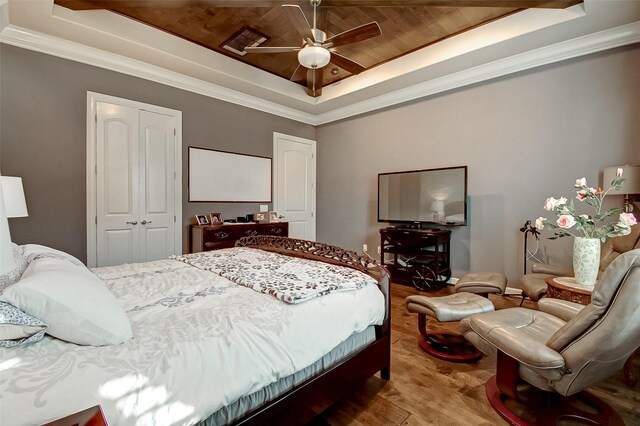 bedroom featuring wood-type flooring, wood ceiling, a tray ceiling, crown molding, and a closet