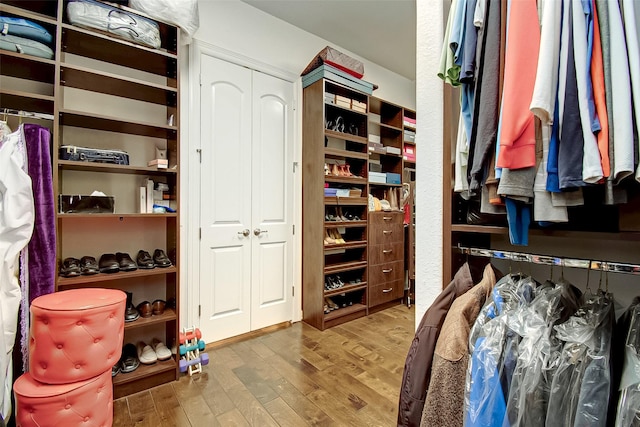 walk in closet with wood finished floors