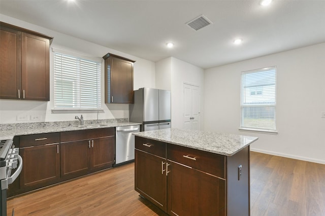 kitchen featuring appliances with stainless steel finishes, a center island, sink, and light hardwood / wood-style flooring