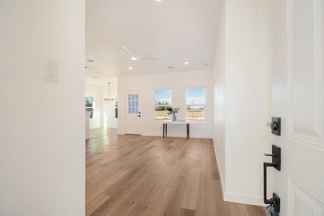 corridor featuring a notable chandelier and light hardwood / wood-style flooring