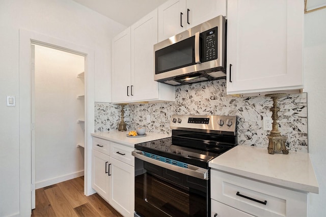 kitchen featuring tasteful backsplash, stainless steel appliances, light hardwood / wood-style floors, and white cabinets