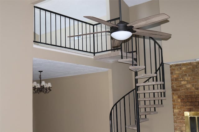 stairs featuring ceiling fan with notable chandelier