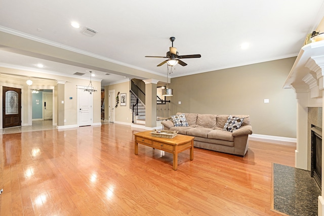 living room featuring light hardwood / wood-style flooring, ornamental molding, ceiling fan, a high end fireplace, and decorative columns