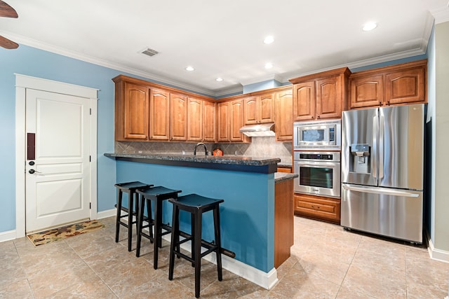 kitchen with backsplash, crown molding, a kitchen breakfast bar, and appliances with stainless steel finishes