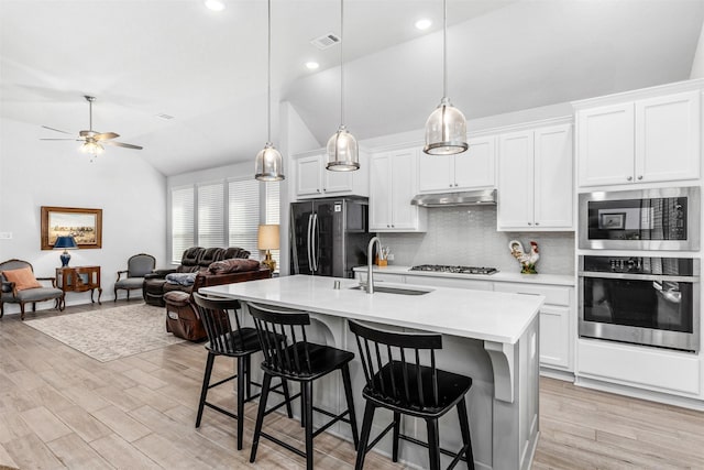 kitchen featuring decorative light fixtures, an island with sink, sink, white cabinets, and stainless steel appliances