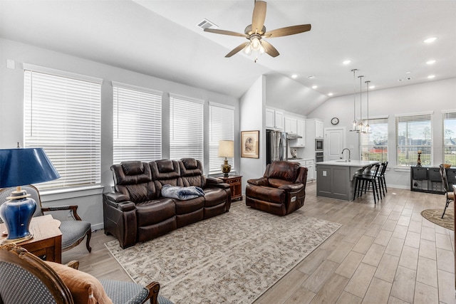 living room with lofted ceiling, sink, ceiling fan with notable chandelier, and light hardwood / wood-style flooring