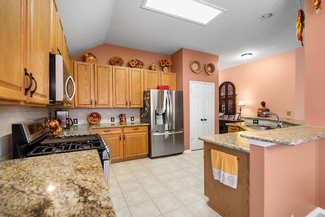 kitchen featuring sink, backsplash, stainless steel appliances, light stone counters, and kitchen peninsula