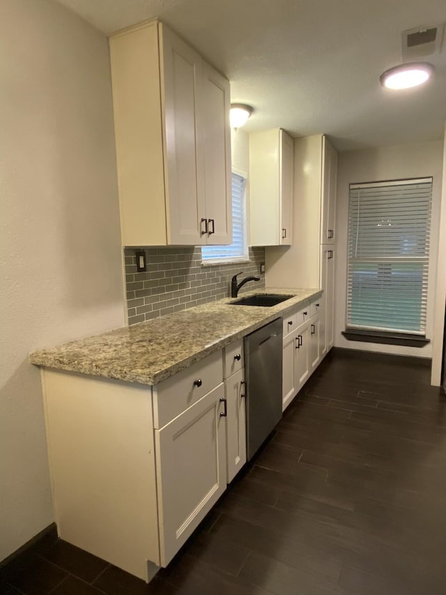 kitchen with light stone counters, stainless steel dishwasher, sink, and white cabinets