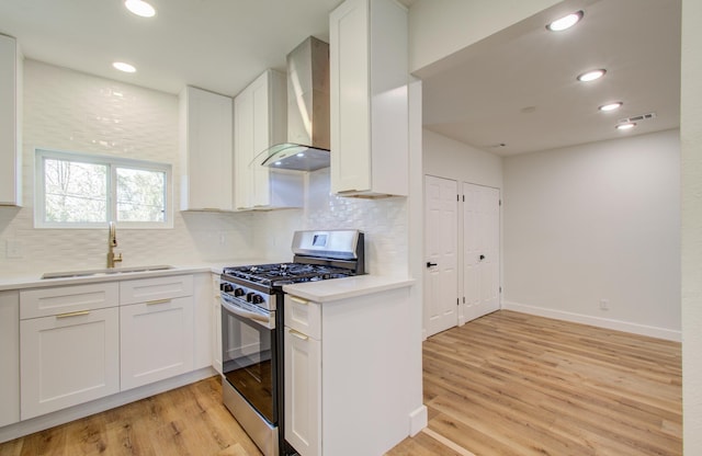 kitchen with white cabinets, wall chimney exhaust hood, and stainless steel gas stove