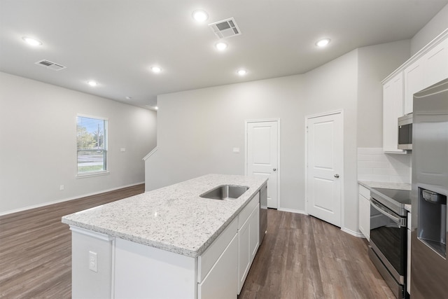 kitchen featuring white cabinetry, light stone counters, wood-type flooring, stainless steel appliances, and a kitchen island with sink