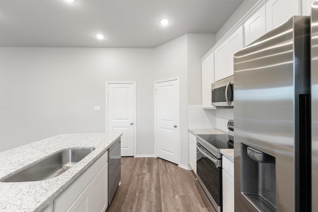 kitchen featuring white cabinetry, appliances with stainless steel finishes, light stone countertops, and sink