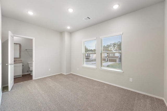 unfurnished bedroom with ensuite bath and carpet floors