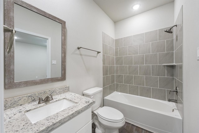 full bathroom featuring vanity, hardwood / wood-style floors, tiled shower / bath combo, and toilet