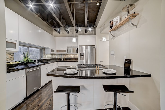 kitchen featuring white cabinetry, stainless steel appliances, a kitchen bar, and sink