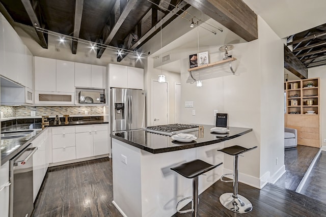 kitchen with white cabinetry, appliances with stainless steel finishes, dark hardwood / wood-style floors, a kitchen breakfast bar, and decorative backsplash