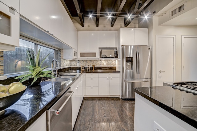 kitchen with white cabinetry, appliances with stainless steel finishes, sink, and dark stone counters