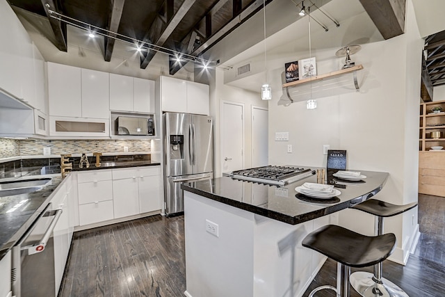 kitchen with white cabinetry, appliances with stainless steel finishes, rail lighting, and tasteful backsplash