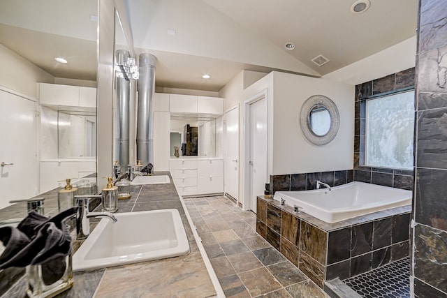 bathroom with vanity, vaulted ceiling, and tiled bath