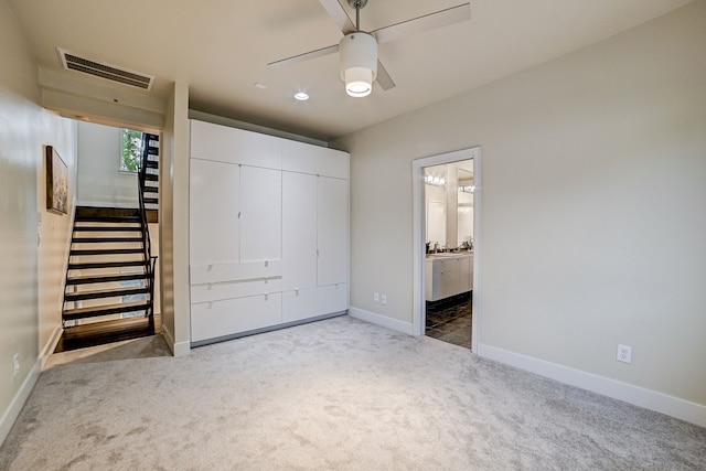 unfurnished bedroom featuring ceiling fan, carpet floors, and ensuite bath