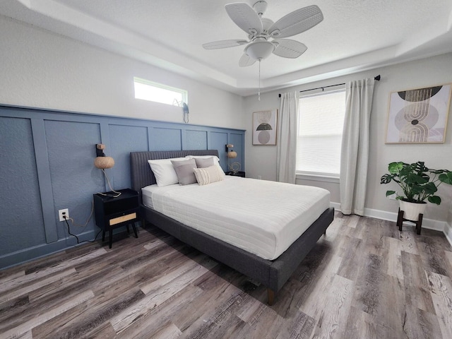 bedroom featuring ceiling fan, dark hardwood / wood-style floors, and a raised ceiling