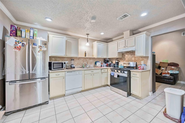 kitchen with ornamental molding, stainless steel appliances, sink, and hanging light fixtures