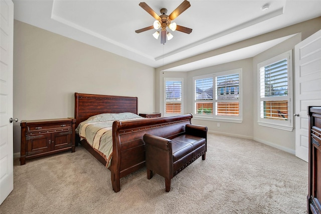 carpeted bedroom with a tray ceiling and ceiling fan