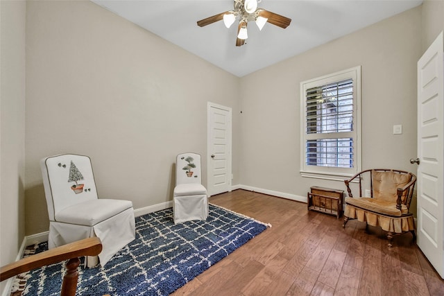 living area featuring dark wood-type flooring and ceiling fan