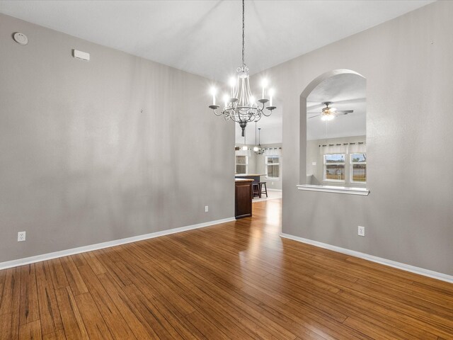 unfurnished dining area featuring ceiling fan with notable chandelier and hardwood / wood-style floors