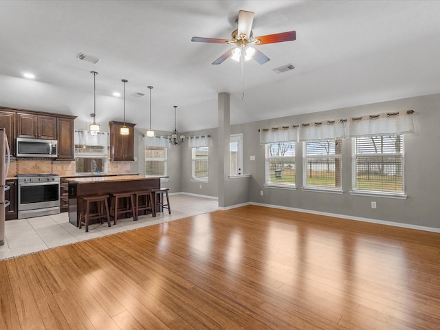 living room featuring lofted ceiling, sink, ceiling fan with notable chandelier, and light wood-type flooring