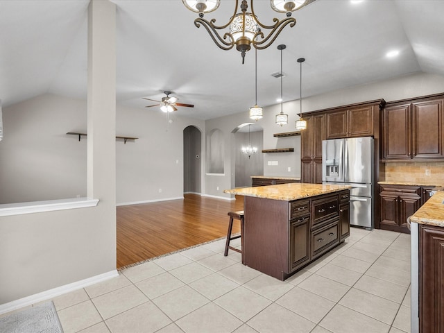 kitchen featuring stainless steel fridge with ice dispenser, dark brown cabinets, a center island, and light tile patterned flooring