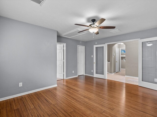 empty room featuring french doors, ceiling fan, and light wood-type flooring