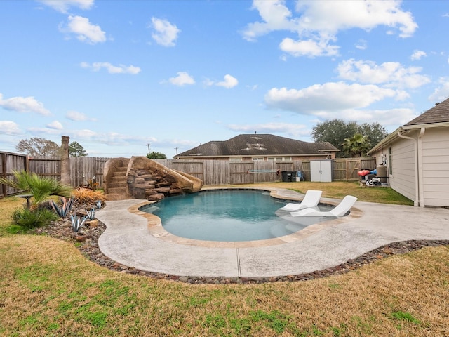 view of swimming pool with a yard, a shed, a patio, and a water slide