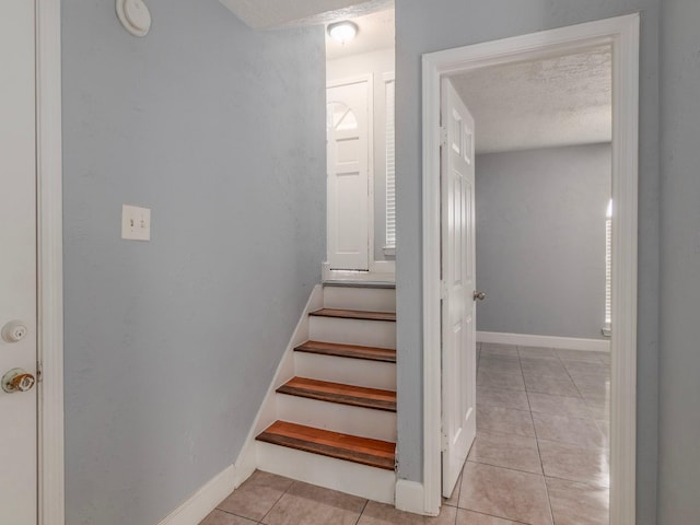 stairs featuring tile patterned floors and a textured ceiling