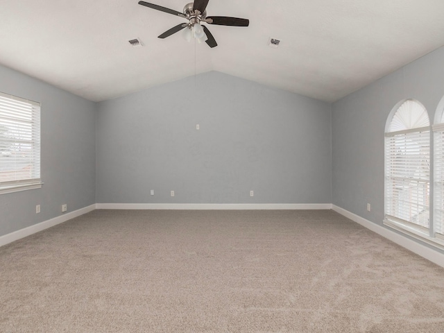 carpeted empty room featuring vaulted ceiling, plenty of natural light, and ceiling fan